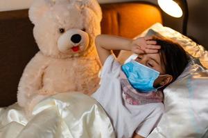 retrato de un niño enfermo con una máscara médica con un juguete suave foto