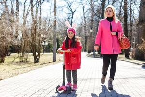 retrato de una joven familia caucásica caminando por la calle niña con scooter foto