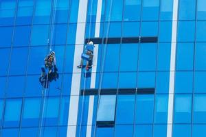 dos trabajadores que lavan las ventanas del edificio moderno. foto