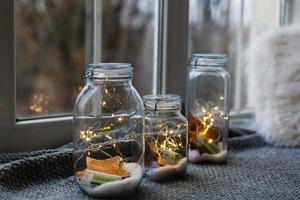 hermosas luces, guirnaldas en un frasco con corazones de felpa roja textil y pétalos de rosa sobre un fondo de madera. concepto de amor o día de san valentín foto