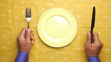 Hand Holding Cutlery With Empty Plate On Wooden Table video