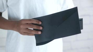 primer plano de la mano del hombre sosteniendo un sobre negro
