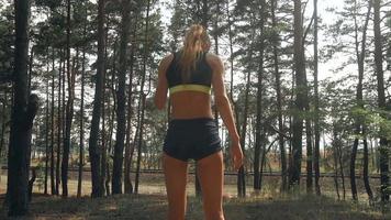 Athletic slim girl with round  buttocks in sports shorts goes through the Woods in slow motion video