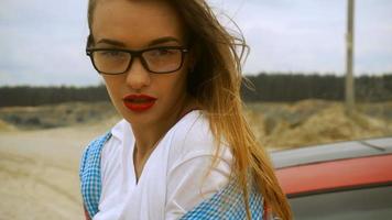 young beautiful blonde with red lips wears a glasses posing on camera and wind moves her hair video