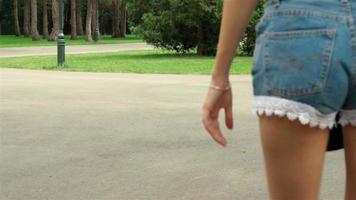 Chica joven delgada con nalgas en pantalones cortos patinando video