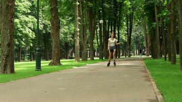 joven delgada en pantalones cortos montando en el parque con ruedas video