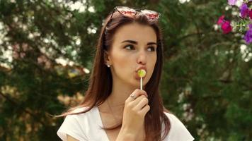 young fashionable girl with sunglasses on her head looks to the side and licks a lollipop video