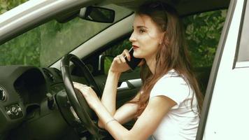 charmante jeune fille à lunettes parlant au téléphone et assise dans la voiture video