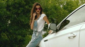 young glamour girl in glasses standing next to the machine and is calling on the phone video