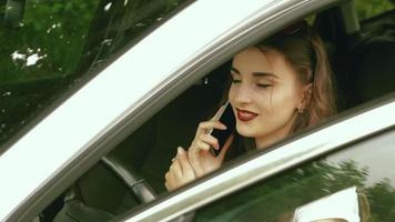 Adolescente morena con estilo se sienta en el auto y dice por teléfono móvil