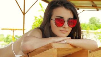 chica joven glamurosa con gafas brillantes bronceadas en la playa de cerca video