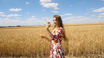 young charming girl stands in a field on the sky background and puts bubbles in slow motion video