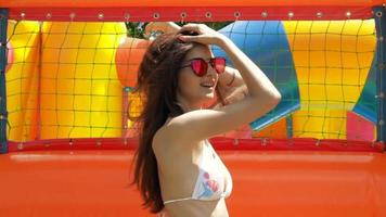 Fantastisk flicka i glasögon och en badning kostym hoppar på ett uppblåsbar madrass på de strand video