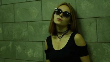 beautiful fashion girl in sneakers and glasses stands in the underpass in the evening video