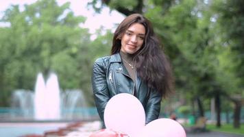 beautiful young brunette holding a large bunch of balloons and smiling close up video