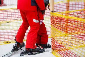 niña de rojo aprendiendo a esquiar con la ayuda de un adulto foto