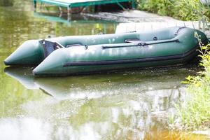 Inflatable boat on the green grass by the lake. photo