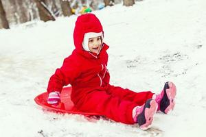 Little girl in red riding ice slide, wintertime photo