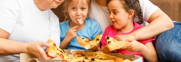 Portrait of family eating pizza on sofa at home photo