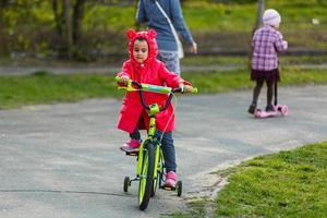 hermosa niña sonriente montando en bicicleta en un parque foto