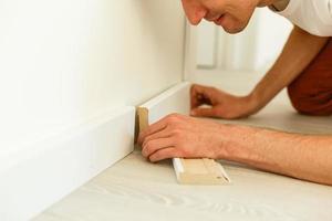 Man putting new skirting board in house photo