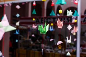 las grullas de papel de origami arcoíris multicolores están suspendidas en gradiente cerca de la guirnalda. foto