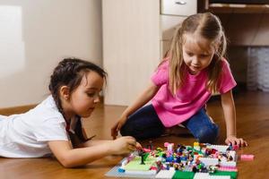 Two cute little children are playing with blocks happy girls at home funny lovely sisters photo