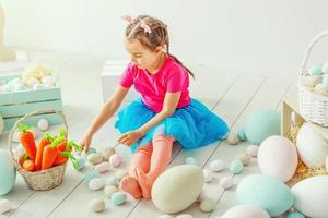 Cute little child girl wearing bunny ears on Easter day. Girl sitting with a basket of Easter eggs. Child girl laughs and enjoys spring and a holiday.