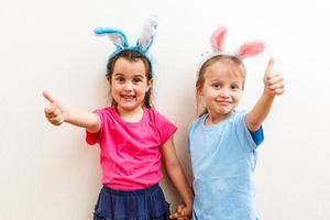 felices pascuas chicas lindas hermanas vestidas como conejos sobre fondo de madera foto