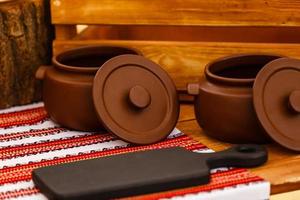 olla de cerámica sucia en la vieja tabla de cocina de madera