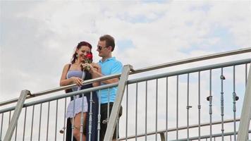The man on the bridge surprised the girl by giving her a flower a red rose video
