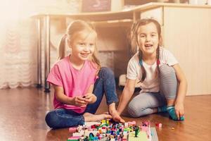 niños felices jugando con bloques en casa o en la guardería. jugando al juego de diseño de construir un rascacielos. juego arquitectónico como juguete educativo para preescolar y jardín de infantes. foto