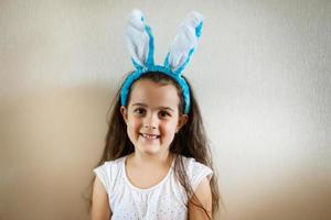 Beautiful little girl with rabbit ears on blue background photo