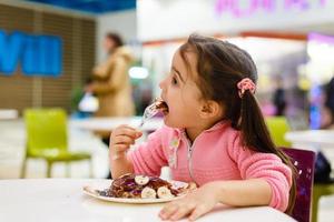 toddler girl eating in outdoor cafe photo