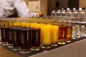 vasos de vidrio con bebidas en la mesa del buffet foto