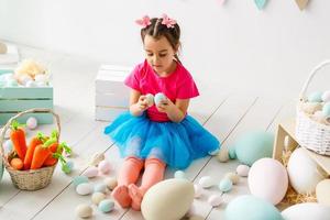 Getting ready to Easter. Lovely little girl holding an Easter egg and smiling with decoration in the background photo