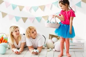Getting ready to Easter. Lovely little girl holding an Easter egg and smiling with decoration in the background photo