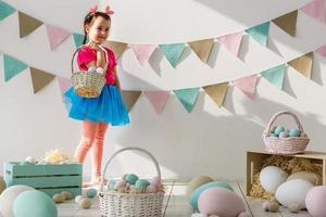 Cute little child on Easter day. Girl holding basket with painted eggs. photo