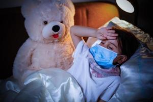retrato de un niño enfermo con una máscara médica con un juguete suave foto