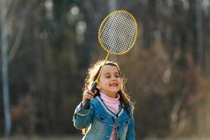 little girl in jeans playing tennis in the park photo