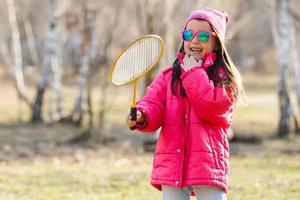 linda niña jugando al bádminton al aire libre en un cálido y soleado día de verano foto