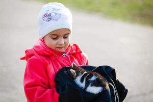 linda niña con su gatito mascota en un cálido día de verano. niños y animales. foto