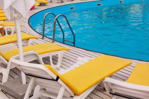 swimming pool with yellows sun lounger photo