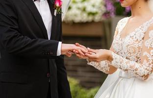 recién casados intercambiando anillos, novia poniendo el anillo en la mano del novio en la oficina de registro de matrimonio