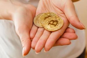 dos bitcoins dorados en la mano símbolo digital de una nueva moneda virtual aislada en blanco foto
