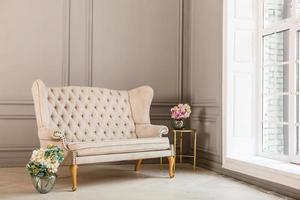 Vintage sofa of soft pink color decorated with flowers and greens stands in a classic room photo