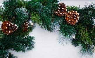 Christmas fir tree branch covered by snow and bauble decor on stone background. Xmas backdrop for your greeting card with space for text photo