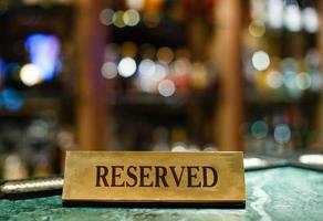 Reserved metal plate with inscription Reserved on an arranged restaurant white table photo