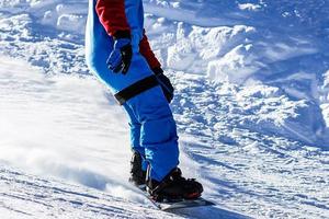 Snowboarder doing a toe side carve with deep blue sky in background photo