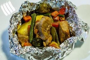 carne al horno con verduras en lámina sobre mesa de madera foto